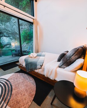 The master bedroom is fitted with a queen size bed with views of the towering cliff next to the cabin