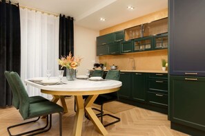 Another view of the dining area and kitchen, showcasing the modern open-plan design and dark green cabinetry.