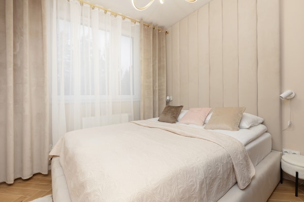 A cozy bedroom with a soft white bedspread, warm lighting, and elegant neutral decor.
