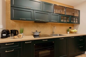 A fully equipped kitchen with dark green cabinets, wooden countertops, and modern appliances.