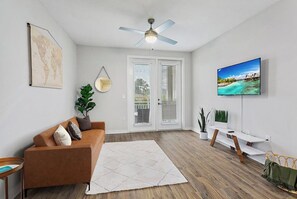 Relaxing living room with sleeper sofa and smart tv. Doors lead to balcony