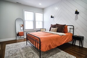 Cozy Bedroom with Queen-Sized Bed, Dual Reading Lamps, and Full Length Mirror.