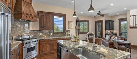 Beautifully appointed kitchen with rustic wooden cabinets, state-of-the-art stainless steel appliances, and a cozy breakfast bar setting—perfect for savoring a morning coffee or an evening glass of wine