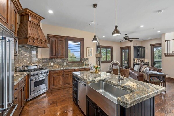 Beautifully appointed kitchen with rustic wooden cabinets, state-of-the-art stainless steel appliances, and a cozy breakfast bar setting—perfect for savoring a morning coffee or an evening glass of wine