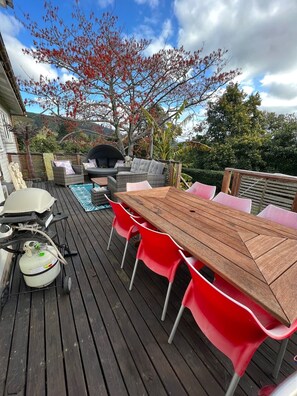 On the deck is a dining table table, mini weber BBQ & comfortable seating.