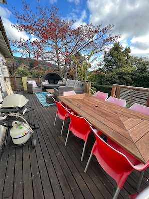 On the deck is a dining table table, mini weber BBQ & comfortable seating.