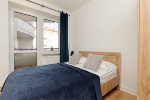 Another view of the bedroom showcasing the bed with blue bedding and a wooden wardrobe, combining warmth and comfort.

