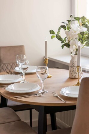 A close-up of a dining table set with elegant glassware, white plates, and a small decorative plant, perfect for a cozy meal.

