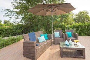 Sitting lounge with table and parasol in the garden of the fenced property of a private villa for rent and vacation