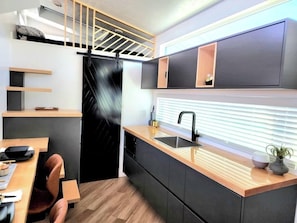 The kitchen is fully equipped with a refrigerator, freezer, microwave, cook-top, and sink with hot/cold water. Enjoy coffee from the coffee maker and ample counter space. Essentials include cookware, dishes, and utensils.