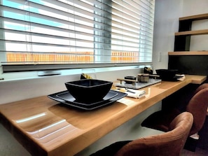 The dining area features a wall-mounted tabletop that maximizes space while providing a cozy spot to enjoy meals. Paired with comfy chairs, it’s the perfect blend of functionality and comfort in a stylish, space-saving design.