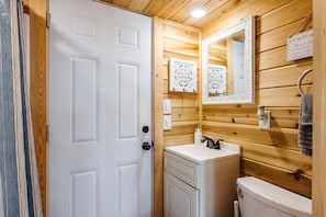 The bathroom features a spacious shower with hot and cold water, fresh towels, and complimentary shampoo. A stylish mirror provides convenience. Everything you need for a comfortable and refreshing stay!