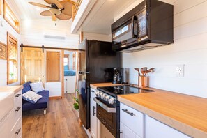 The kitchen is fully equipped with a refrigerator, freezer, microwave, stovetop and oven, and sink with hot/cold water. Enjoy coffee from the coffee maker, with cookware, dishes, utensils, and plenty of storage cabinets to keep everything organized.
