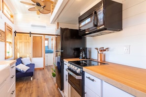 The kitchen is fully equipped with a refrigerator, freezer, microwave, stovetop and oven, and sink with hot/cold water. Enjoy coffee from the coffee maker, with cookware, dishes, utensils, and plenty of storage cabinets to keep everything organized.