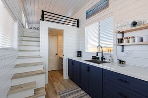 The kitchen is fully equipped with a refrigerator, freezer, microwave, cooktop, and sink with hot/cold water. Enjoy coffee from the coffee maker, with cookware, dishes, utensils, and plenty of storage cabinets to keep everything organized.