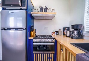 The kitchen is fully equipped with a refrigerator, freezer, microwave, stovetop and oven, and sink with hot/cold water. Enjoy coffee from the coffee maker, with cookware, dishes, utensils, and plenty of storage cabinets to keep everything organized.