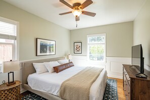 Bedroom 1 with a sleek TV rack and abundant natural light from the window.