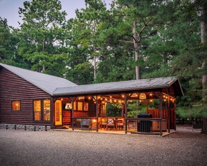 Cozy log cabin retreat with sparkling outdoor lights and a welcoming porch.