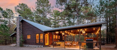 Cozy log cabin retreat with sparkling outdoor lights and a welcoming porch.