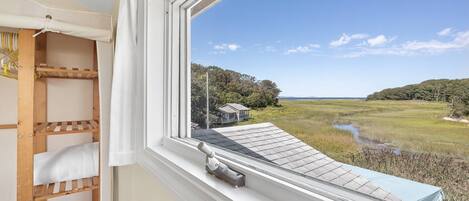 View of the marsh and ocean at high tide from the upstairs primary queen bedroom with mini-split AC unit and standing closet storage.