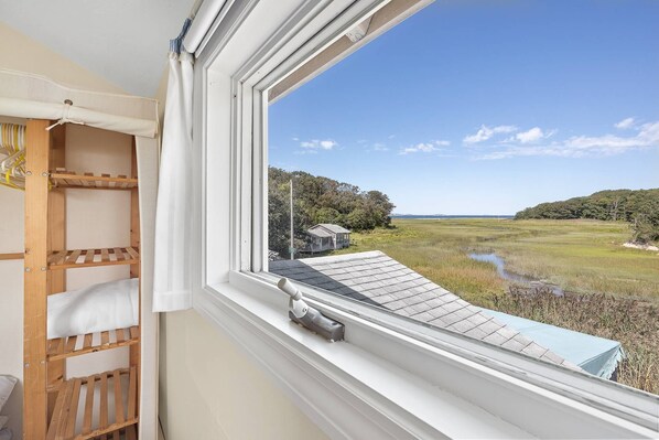 View of the marsh and ocean at high tide from the upstairs primary queen bedroom with mini-split AC unit and standing closet storage.