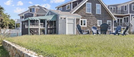 View of the house from the backyard.  You ca see screened porch, outdoor shower enclosure, and outdoor furniture