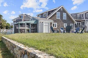 View of the house from the backyard.  You ca see screened porch, outdoor shower enclosure, and outdoor furniture
