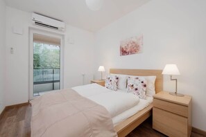 A bedroom with a bed covered in light bedding, wooden bedside tables, and a lamp, creating a cozy atmosphere.