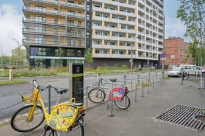 An exterior view of a modern building with a bike rental station, surrounded by a well-organized urban area.