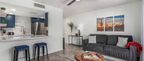 Warm & Inviting living space featuring designer furnishings and decor with a sleeper sofa and a flat-screen Smart TV for entertainment. Overlooking the fully equipped kitchen.