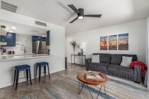 Warm & Inviting living space featuring designer furnishings and decor with a sleeper sofa and a flat-screen Smart TV for entertainment. Overlooking the fully equipped kitchen.