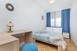 A cozy bedroom with a wooden bed, blue bedding, and a desk, creating a practical and comfortable sleeping space.

