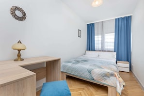 A cozy bedroom with a wooden bed, blue bedding, and a desk, creating a practical and comfortable sleeping space.