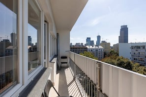 A spacious balcony with a view of the city skyline, featuring railings and ample space for relaxation.