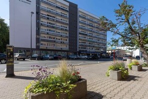 An exterior view of a residential complex with a paved walkway, landscaping, and a clean urban environment.