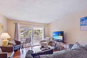 Bright Living Room with Streaming and Balcony Access - Catch the game, your favorite series, or just a breeze—this airy St. Simons vacation rental living room connects indoor comfort with outdoor views in one easy layout.