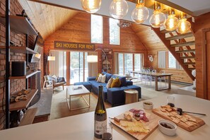 The open-plan area flows from kitchen to living room to deck via glass doors.