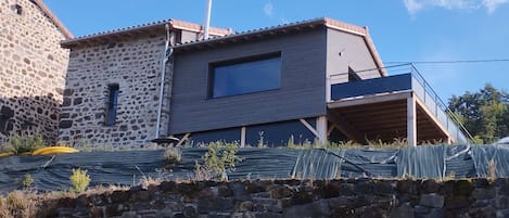 Chalet bâti en pierres basaltiques et bois respectant le caractère du Village 