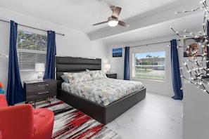 Enjoy a quiet night in the fourth bedroom with a large 50" TV, reading chair, ceiling fan, and plenty of space.