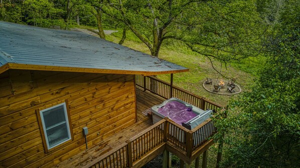 Escape to nature in this charming cabin, featuring a private deck and a relaxing hot tub surrounded by lush greenery.