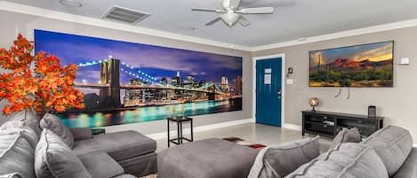 Living Room adorned with New York-themed wall decor, featuring ample seating, flat-screen TV, and access to the backyard.