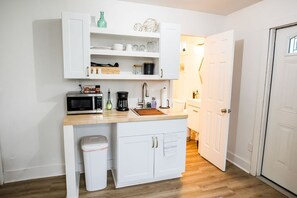 A compact kitchen area equipped with a toaster oven, microwave, and essential dishes offers convenience for preparing quick meals. 