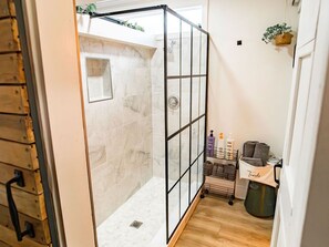 A large, beautiful bathroom features an exquisite walk-in shower adorned with elegant marble tiles and a sleek glass enclosure. With its stylish design and ample space, this bathroom provides a tranquil retreat for relaxation and rejuvenation.