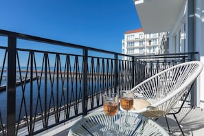 A balcony with a comfortable seating area, offering picturesque views of the waterfront and surrounding buildings.

