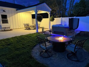 Beautifully remodeled outdoor gathering space with covered patio table, hot tub and fire table.