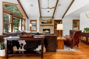 The open living room boasts high ceilings, a large flatscreen TV and a cozy gas fireplace.