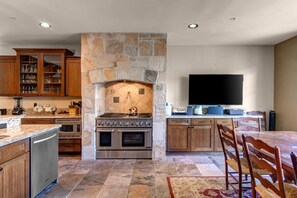 - Whip up gourmet meals with a full suite of stainless appliances and double ovens
- Beautiful stonework and granite counters elevate this rustic chic kitchen space
- Wall mounted TV and spacious layout make it ideal for cooking and gathering