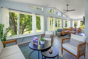 Sunroom with lounge seating, television, and expansive views of the natural surroundings