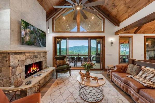 Living room with custom designer furniture, stone and concrete-tile fireplace, and 12-foot sliding doors that perfectly frame and bring the mountains inside.