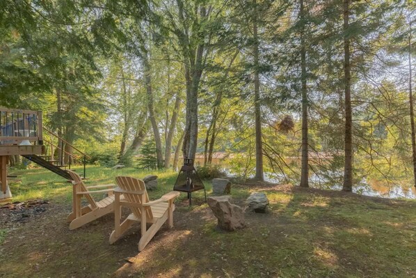 Relax by the serene riverfront surrounded by tall trees and cozy seating
